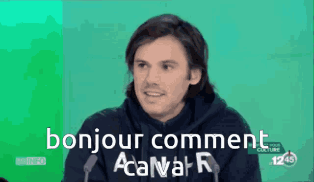 a man speaking into a microphone with the words bonjour comment on the screen behind him