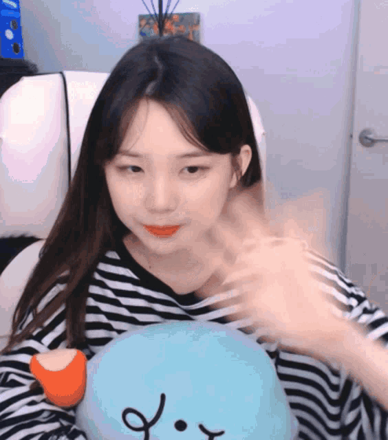 a girl in a striped shirt is sitting in a chair holding a stuffed animal with the letter o on it