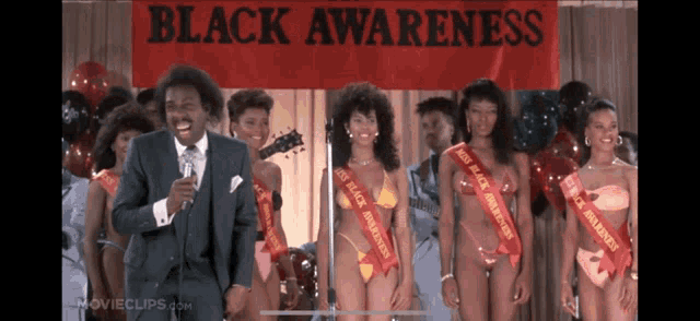 a man stands in front of a black awareness sign