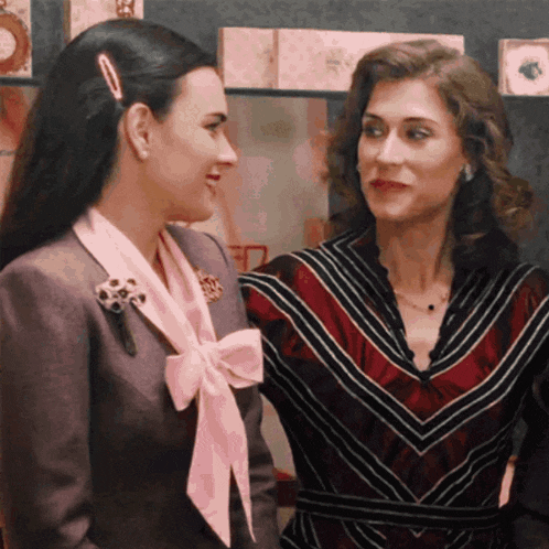 two women are standing next to each other and one has a pink bow in her hair