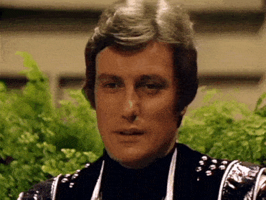 a close up of a man 's face in front of a plant