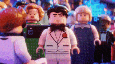 a lego man in a tuxedo is standing in front of a group of lego figures .