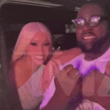 a man and a woman are sitting next to each other at a party and the woman is wearing glasses .