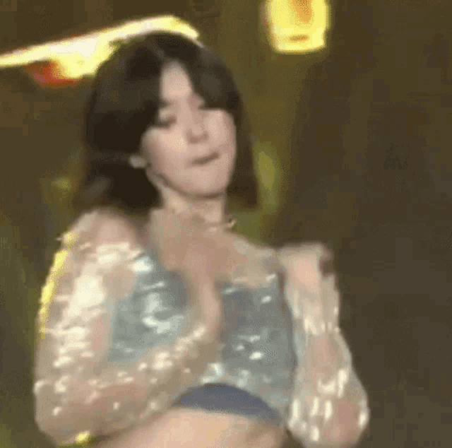 a woman in a blue top is dancing on a stage in front of a crowd .