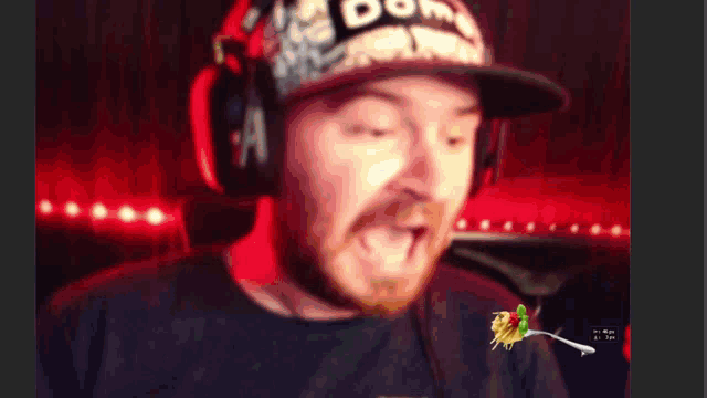a man wearing a hat with the word dome on it is eating spaghetti
