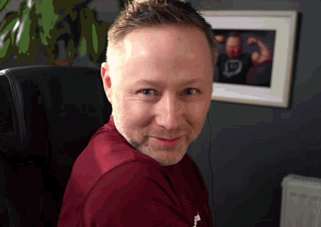 a man wearing a maroon shirt with a twitch logo on his shirt