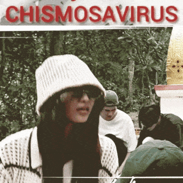 a woman wearing a white hat and sunglasses stands in front of a sign that says chismosaurus