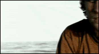 a man in a brown shirt is standing in front of a body of water .