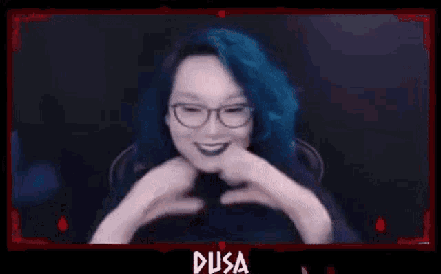 a woman with blue hair is making a heart with her hands .