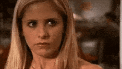a close up of a woman 's face with long blonde hair making a funny face .