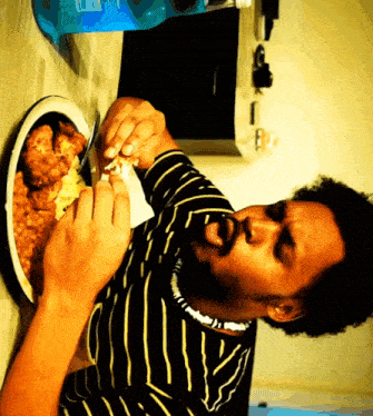a man in a striped shirt is eating food from a plate