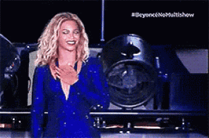 a woman in a blue dress is smiling and holding her hands to her chest .
