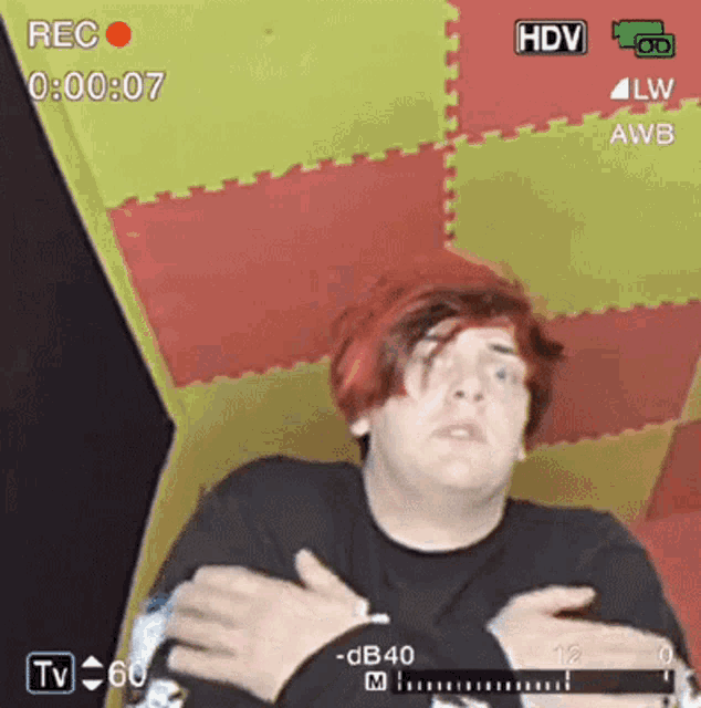 a man with red hair and a black shirt is being recorded on a tv .
