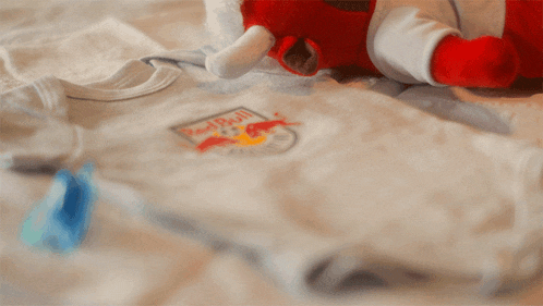 a baby 's bodysuit with a redbull logo on it