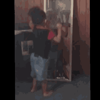a young boy is standing in front of a mirror looking at himself