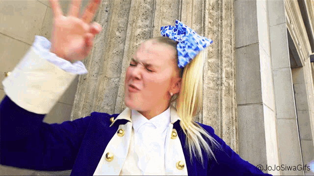 a girl with a blue bow in her hair is wearing a military uniform