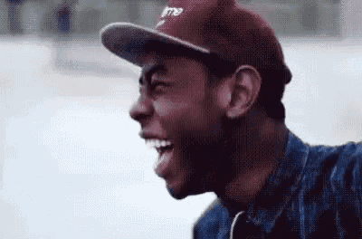 a man wearing a baseball cap and a denim jacket is smiling .