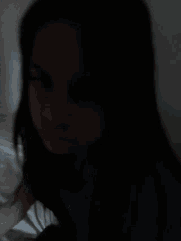 a woman with long black hair is laying on a bed with her eyes closed