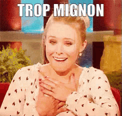 a woman is smiling with her hands on her chest and the words trop mignon are above her .