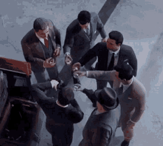 a group of men in suits and hats are standing in a circle holding glasses .