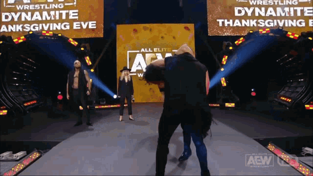 a wrestler stands on a stage in front of a sign that says dynamite