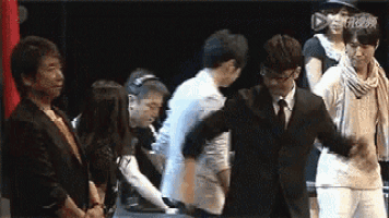 a group of people are standing next to each other on a stage and one of them is hugging another person .