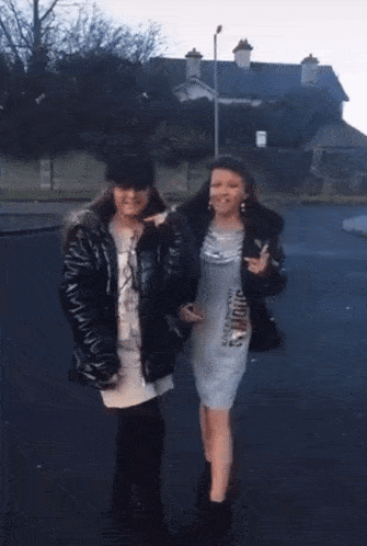 two women are walking down a street and one is wearing a shirt that says ' i love you ' on it