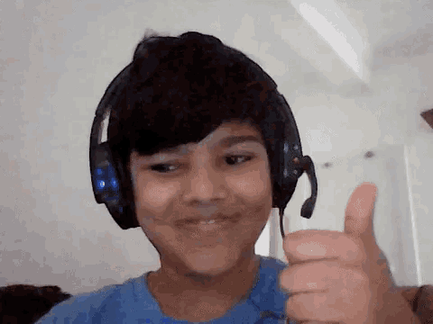 a young boy wearing headphones is giving a thumbs up sign