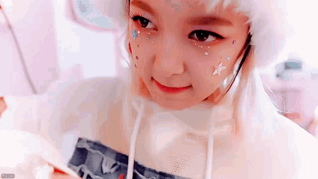 a little girl with stars on her face is wearing a white hat and a white sweater .