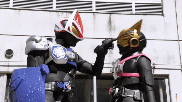 two kamen riders are standing next to each other with one pointing at the other