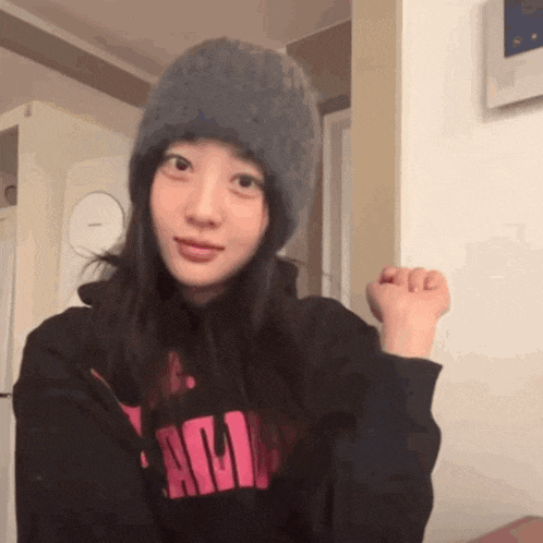 a woman wearing a hat and a hoodie that says ' am ' on the front