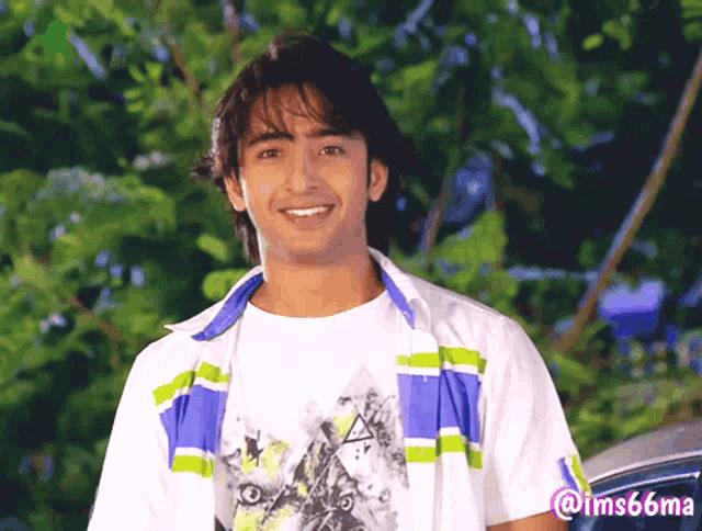 a young man wearing a white shirt and a blue and green striped jacket smiles for the camera