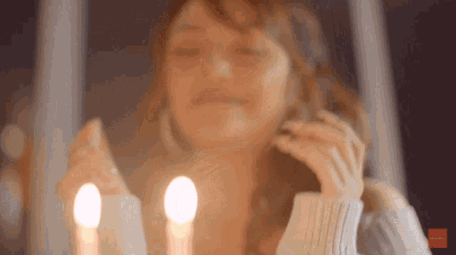 a woman is sitting in front of candles with her eyes closed and a red sticker that says ' vodafone '