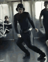 a man wearing a hat and glasses is dancing on a subway