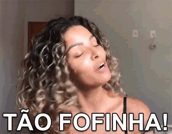 a woman with curly hair says " tao fofinha " in front of her