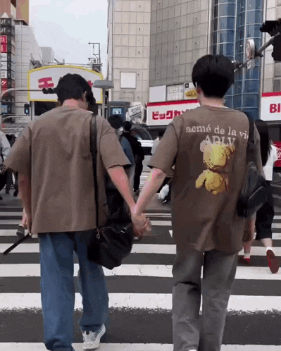 two people crossing a street with one wearing a shirt that says aemé de la vie