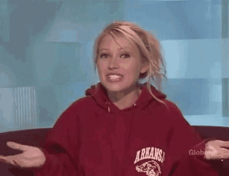 a woman in a red arkansas sweatshirt is sitting on a couch with her arms outstretched .