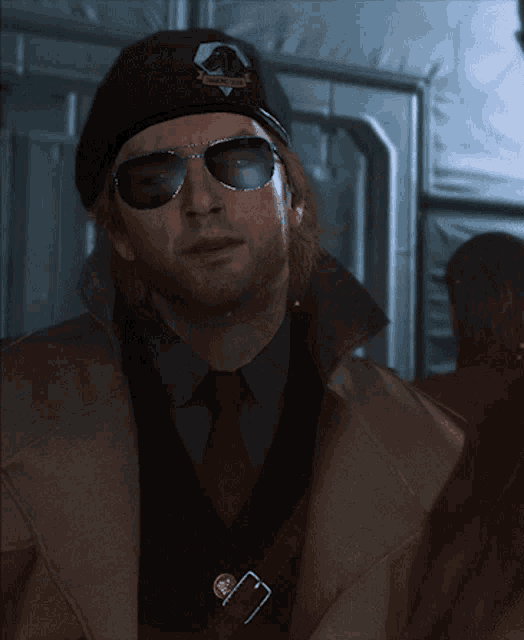 a man wearing sunglasses and a beanie with a badge that says ' military ' on it