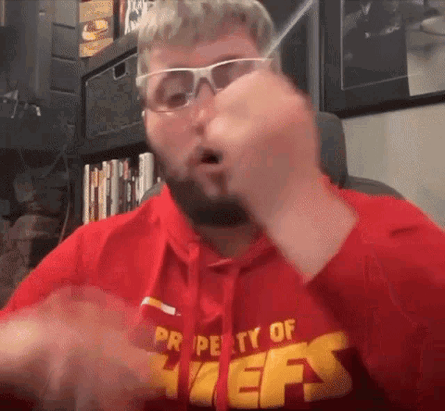 a man wearing sunglasses and a red shirt that says property of the chiefs