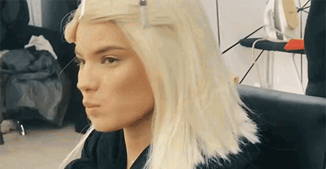 a woman with blonde hair is sitting in a chair with her hair in a ponytail .