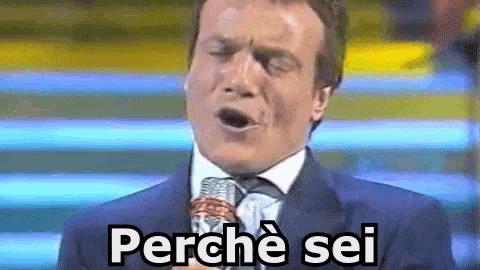 a man in a suit and tie is singing into a microphone and the words perche sei are on the screen