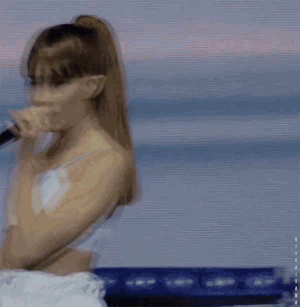 a woman singing into a microphone with a ponytail