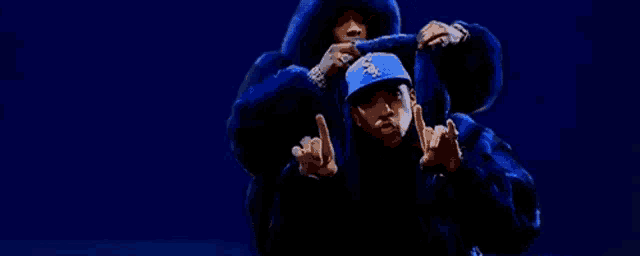a couple of men in blue fur coats are dancing on a blue background .
