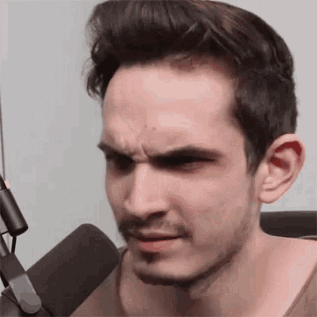 a man with a beard is making a face in front of a microphone .