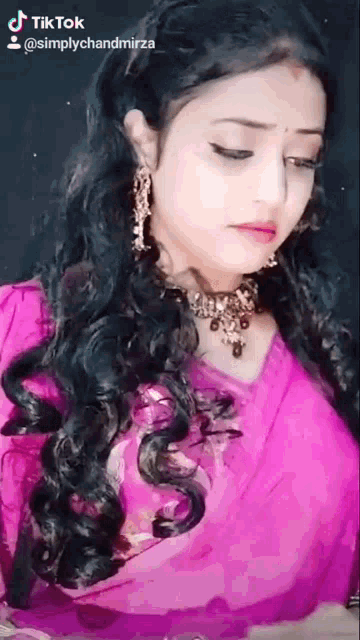 a woman is wearing a pink top and a necklace and has a tik tok account