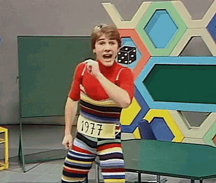 a man wearing striped pants with the year 1977 on his waist is standing on a stage .