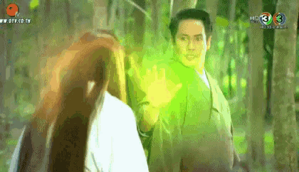 a man and a woman are standing next to each other in a forest with a green light coming from their hands .