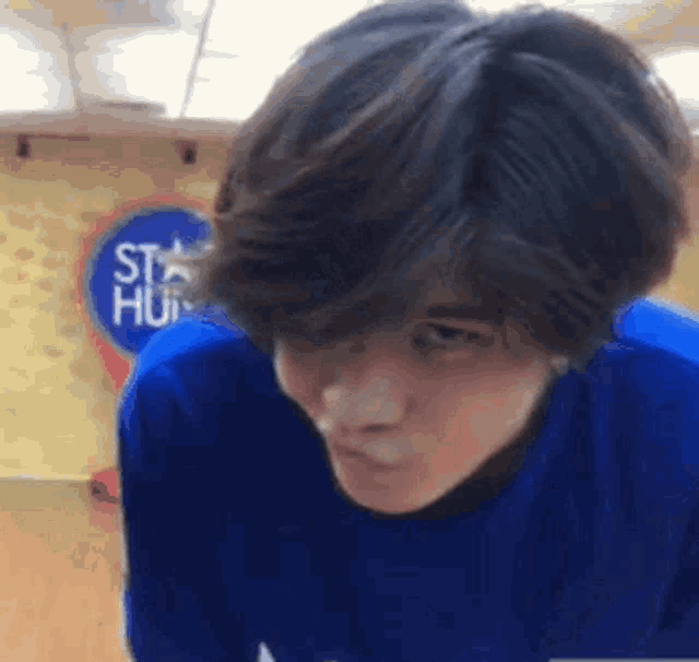 a young man wearing a blue shirt is making a funny face in front of a sign that says star hut