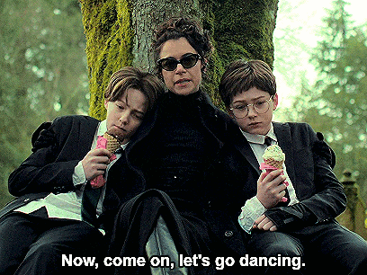 a woman and two boys are sitting under a tree with the words now come on let 's go dancing above them