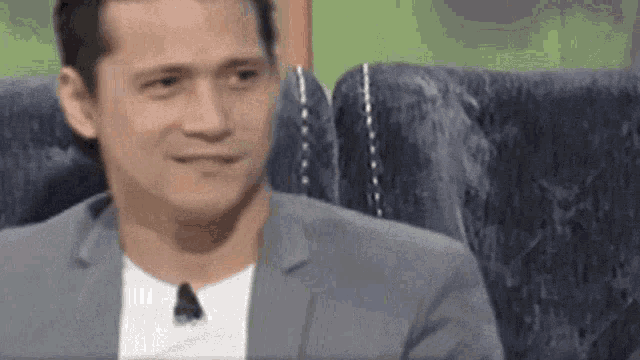 a man in a suit and white shirt is sitting on a couch .